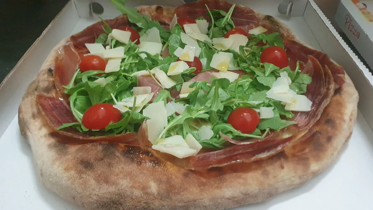 Pizza con crudo, rucola, grana e pomodorini
